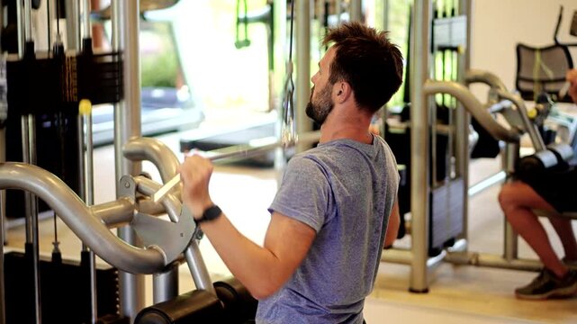 Man lifting weights doing cable pushdown exercises in gym	