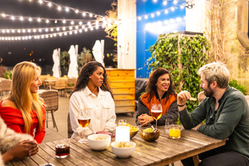Friends talking relaxed in a night terrace bar