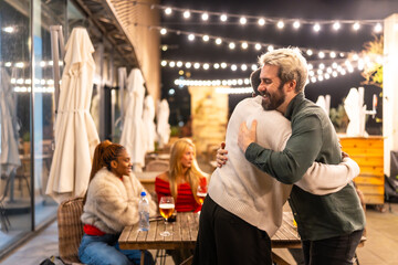 Friends hugging when arriving at meeting in a bar