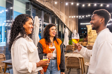 Multi-ethnic friends talking while drinking beer at night