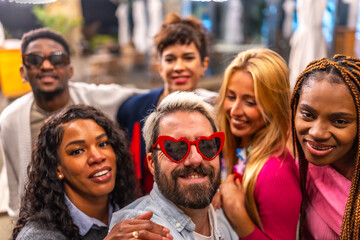 Man with heat shape sunglasses taking selfie with friends outdoors