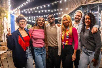 Portrait of multi-ethnic friends standing at bar terrace at night