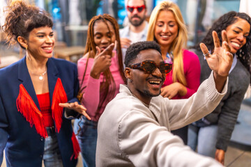 Multi-ethnic friends waving at camera taking selfie at party