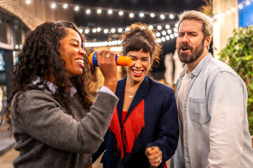 Latin woman singing karaoke next to friends at night party