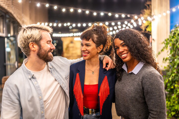 Happy friends embracing smiling in a roof terrace at night