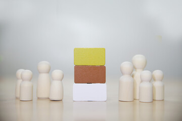 Competition concept. Human figure on wooden cube and other ones behind against black background, closeup