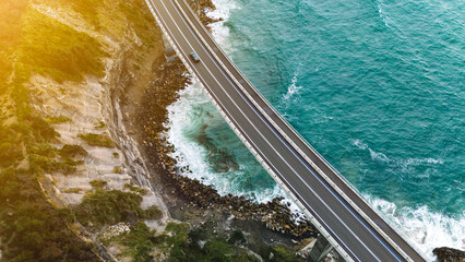Fading golden sunlight adds color when looking down at a coastal highway bridge.
