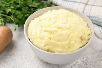 Mashed potatoes in white bowl on grey concrete background. Healthy food