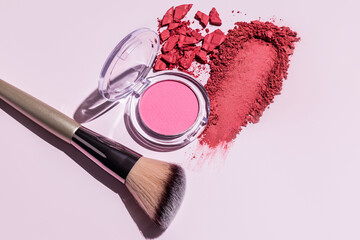 A sample of pink blush, an open pack of soft pink blush, a makeup brush on a light background....