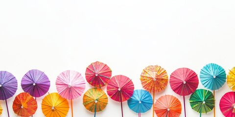 A collection of vibrant, multi colored cocktail drink umbrellas or paper parasols is beautifully arranged along the bottom border against a clean white background, enhancing the festive feel.