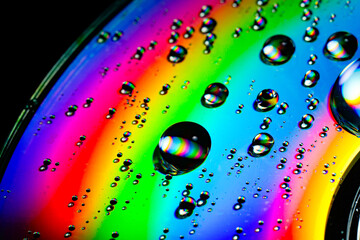 Abstract macro photo of extremely colorful water drops on dvd surface