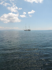 Blaues Meer und blauer Himmel umrahmen ein Segelschiff zwischen Inseln