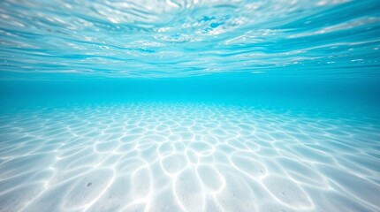Serene underwater scene showing sunlit ripples on sandy ocean floor with clear turquoise water