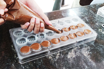 Filling chocolate using piping bag to a chocolate mould