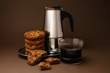 The coffee pot is on a tray, cookies and coffee in a glass
