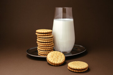 milk in a glass on a tray and cookies with chocolate next to it
