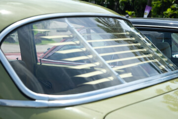Fototapeta premium A close-up of a classic car’s rear window featuring vintage sunshade louvers. The chrome detailing and reflections enhance the nostalgic, retro, and timeless automotive appeal.