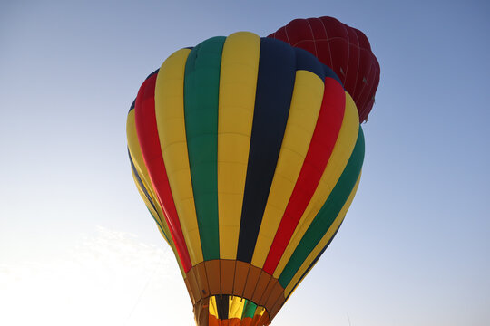 Colorful hot air balloon preparing for liftoff under a clear sky.