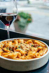 Pasta with red sauce served with a glass of red wine by the window.