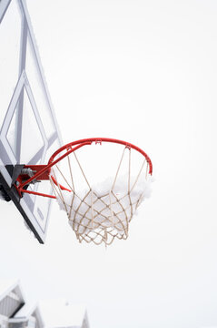 Snow-covered basketball hoop during winter in a suburban neighborhood