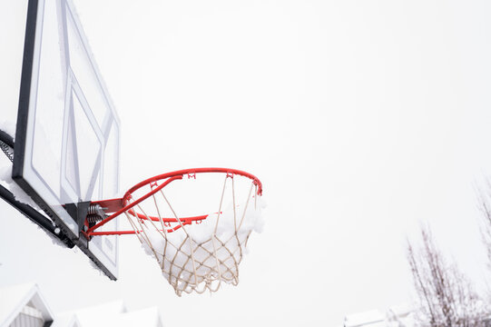 Snow-covered basketball hoop during winter in a suburban neighborhood