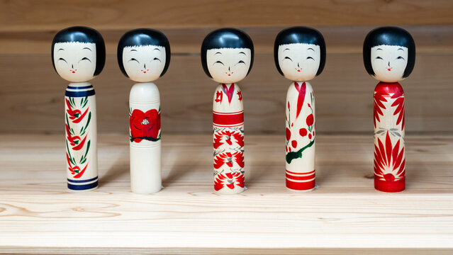JAPAN - Dec 22, 2024: Five colorful Kokeshi dolls with distinct patterns and expressions, showcasing traditional Japanese craftsmanship on a wooden surface
