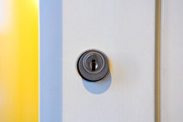 Close-up of keyhole of white metal frame glass door outside of closed door of apartment building on a winter morning. Photo taken January 9th, 2025, Zurich, Switzerland.