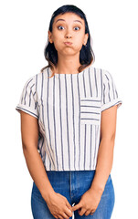Fototapeta premium Young woman wearing casual clothes puffing cheeks with funny face. mouth inflated with air, crazy expression.
