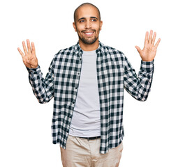 Naklejka premium Hispanic adult man wearing casual clothes showing and pointing up with fingers number nine while smiling confident and happy.