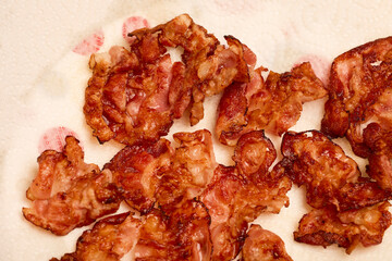 fried bacon slices placed on a paper napkin