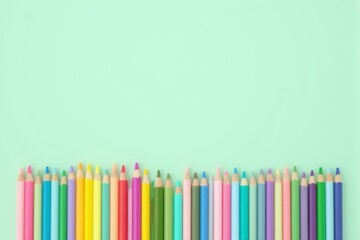 A neat row of pastel colored pencils on a matching pastel mint background