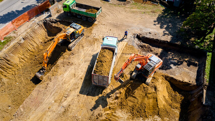 Ariel view excavator is loading a truck with ground on building site
