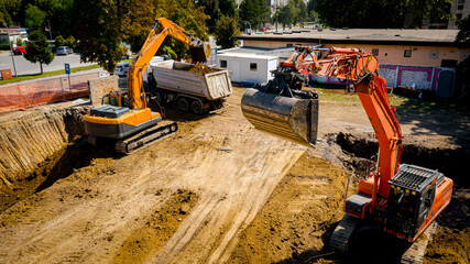 Ariel view excavator is loading a truck with ground on building site