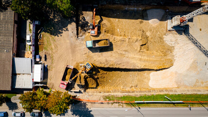 Ariel view excavator is loading a truck with ground on building site