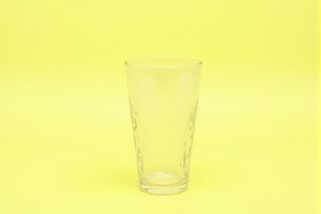 A single glass tumbler with textured patterns displayed on a pastel lemon background