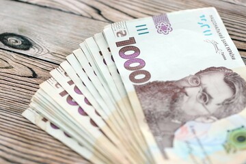 Big amount of ukrainian new one hundred hryvnia money bills with modern design on wooden background. Financial concept, business