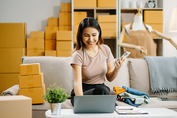 Young business owner woman prepare parcel box and standing check online orders for deliver to...