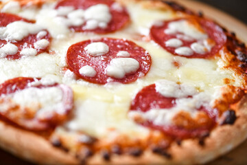 Pizza with salami and mozzarella cheese. Wooden background. Soft focus. Close up.