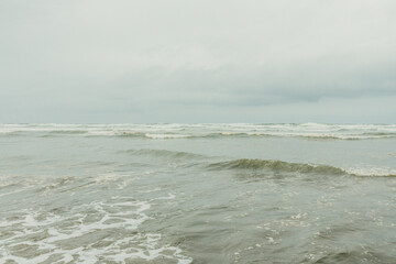 tranquil seascape with seafoam waves on overcast day on Washington State coastal beach