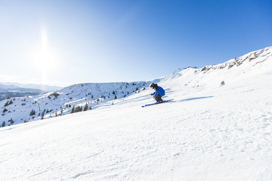 Skier carving down snowy slopes in sunny Kitzb&uuml;hel, Austria