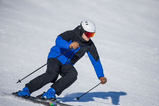 Skilled skier carving dynamic turns on a sunlit snowy slope