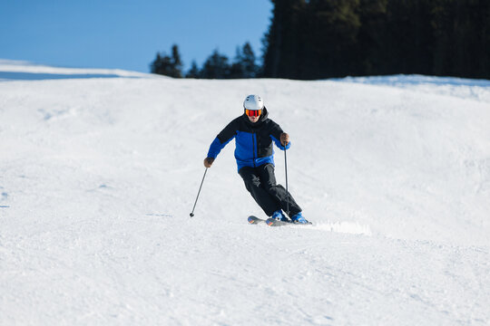 Skier carving on a snowy slope in Kitzb&uuml;hel under a bright blue sky