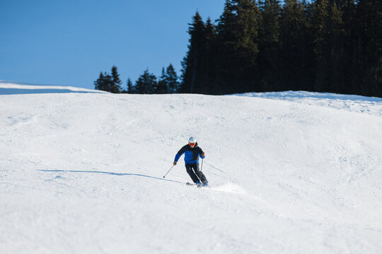 Skier carving on a snowy slope in Kitzb&uuml;hel under a bright blue sky