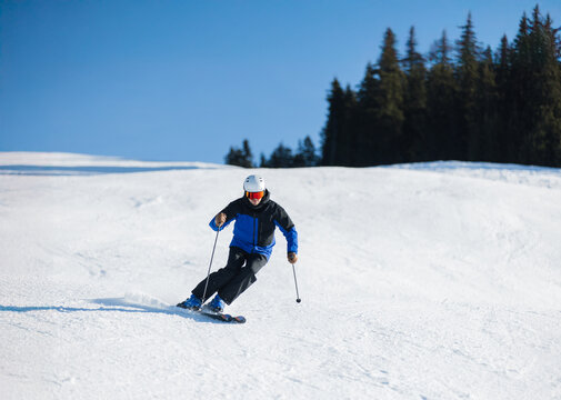 Skier carving on a snowy slope in Kitzb&uuml;hel under a bright blue sky
