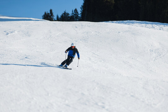 Skier carving on a snowy slope in Kitzb&uuml;hel under a bright blue sky
