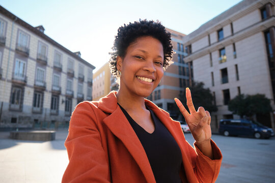 Smiling woman making peace sign in urban setting