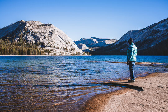woman stands on shore of Tenaya Lake, Yosemite on cold day