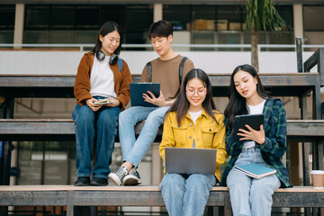 Young people college students is reading a book while relaxing sitting on grass in a campus park