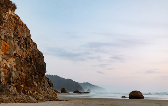 Coastal cliffside with a serene ocean and misty horizon at dusk