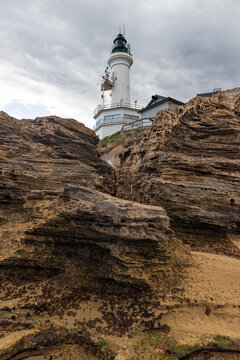 Lighthouse behind weathered rocks on a cloudy day Point Lonsdale